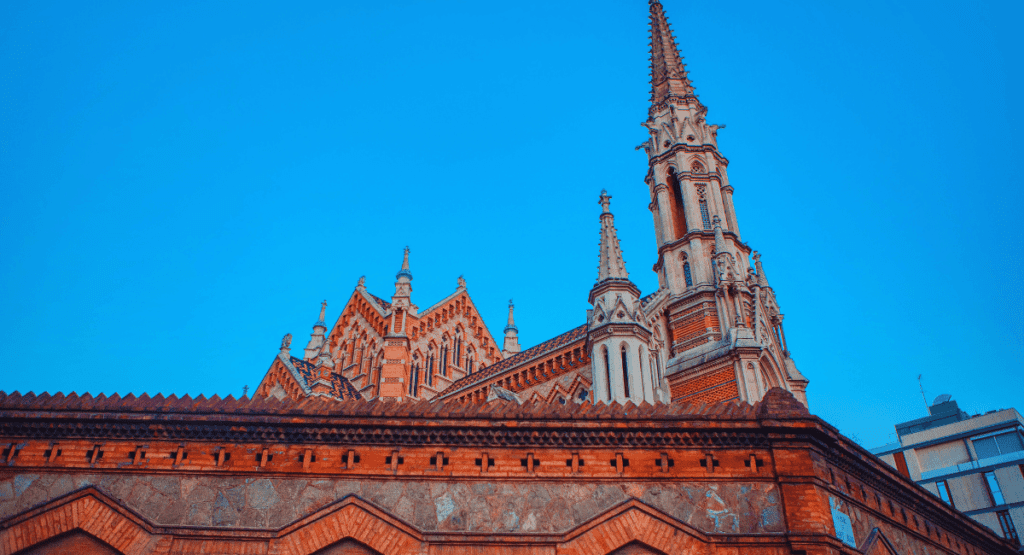 Close-up view of the intricate Gothic architecture of Sant Francesc Xavier church, featuring ornate spires and detailed brickwork against a clear blue sky."