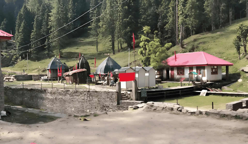 Gir Ganga Temple, a picturesque Hindu shrine nestled amidst the Himalayas in Gir Ganga, Himachal Pradesh. The temple features a central dome and surrounding smaller shrines, surrounded by green meadows and towering pine trees.