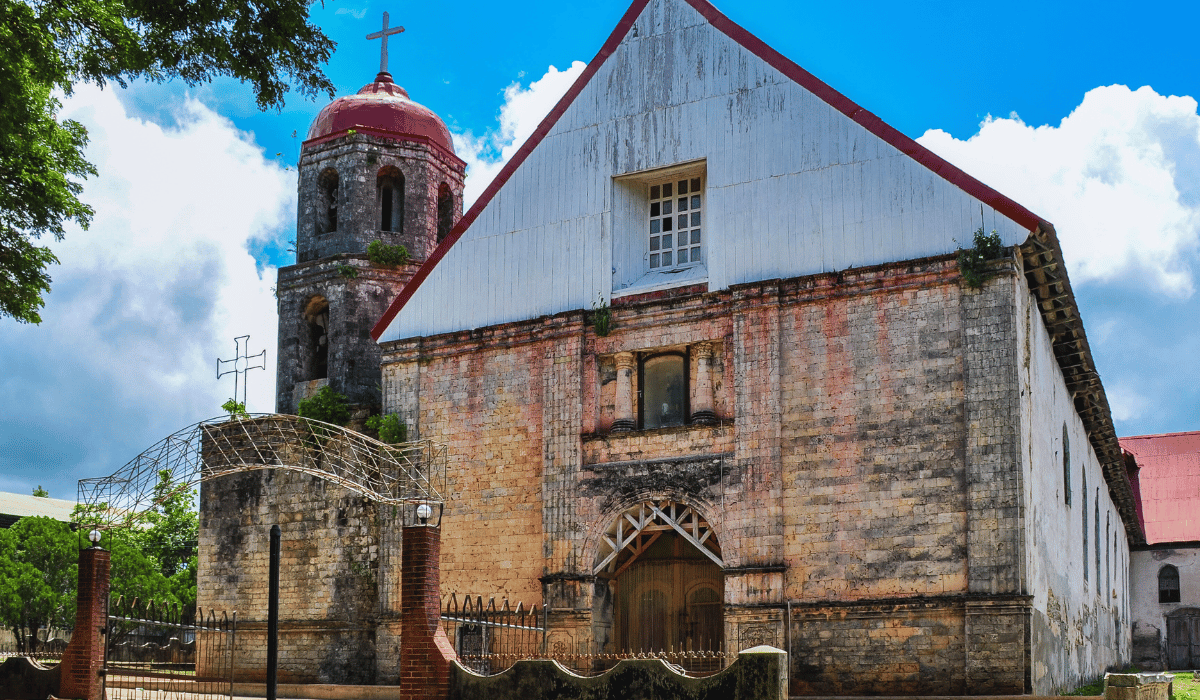 The image shows Lazi Church, also known as San Isidro Labrador Parish Church. It is a historic Roman Catholic church located in Lazi, Siquijor, Philippines. The church is known for its coral stone construction, large wooden convent, and colonial architecture, reflecting its historical and cultural significance in the region.