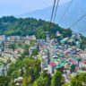 "Panoramic vista of the colorful buildings and steep hills of Gangtok, Sikkim, as seen through the cables of the city's famous aerial tramway."